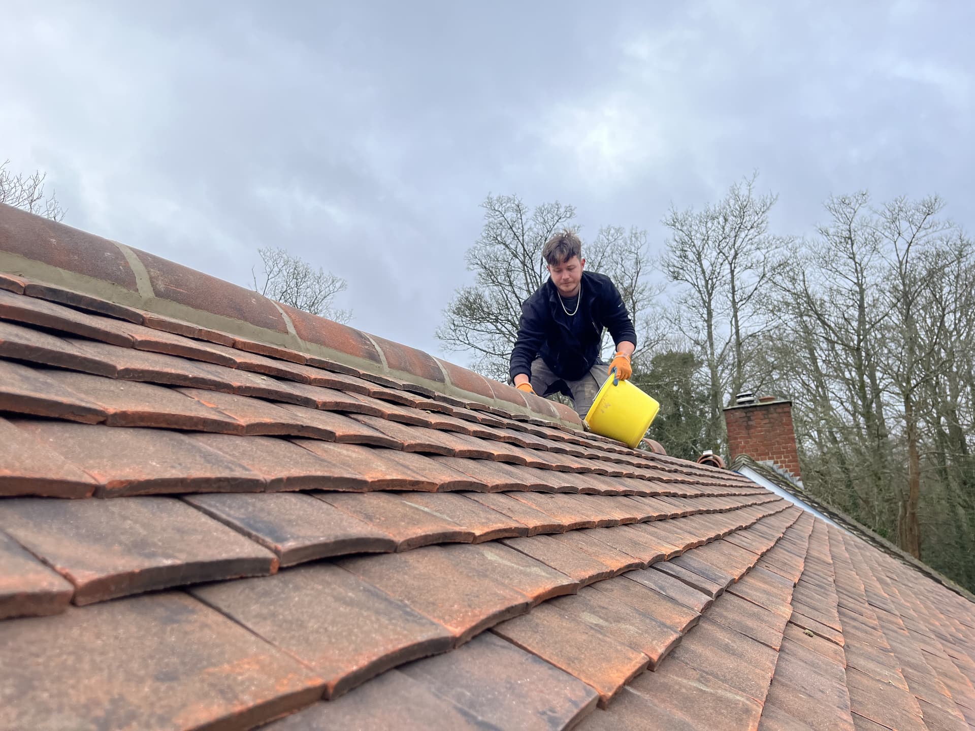 Worker on roof with mortar bucket