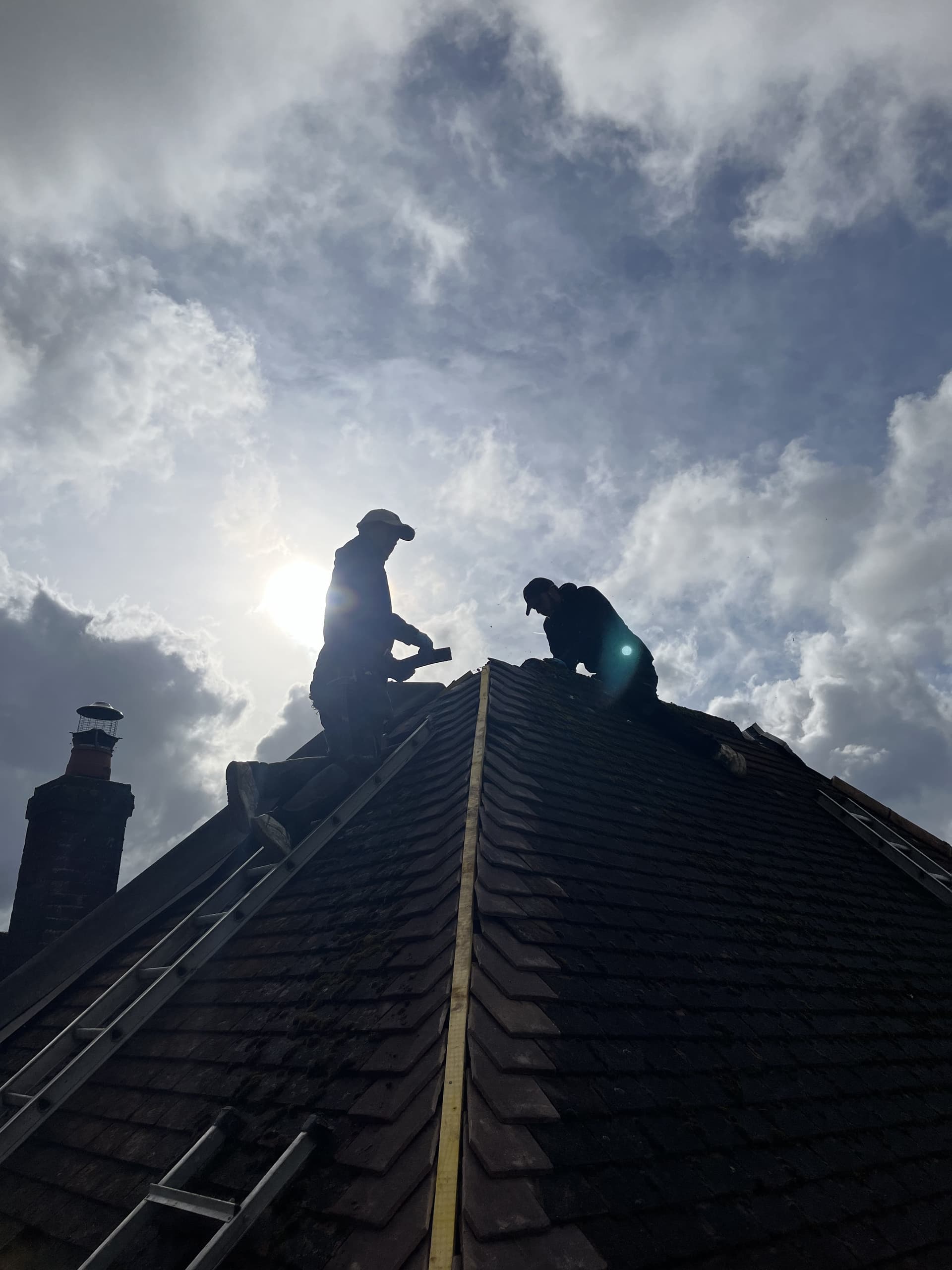 Roofers silhouetted on ridge at sunset