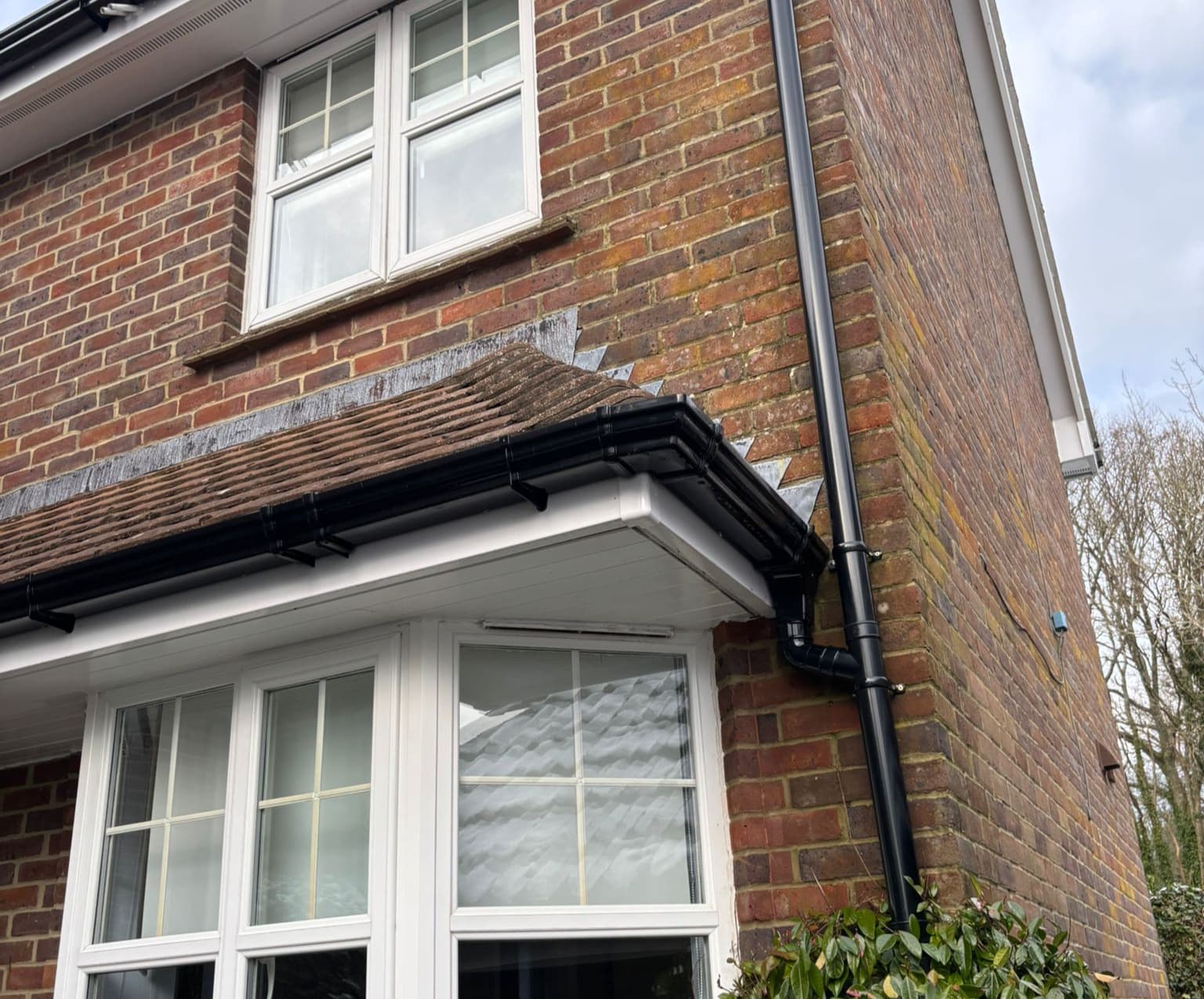 Black ogee guttering and downpipe on brick house