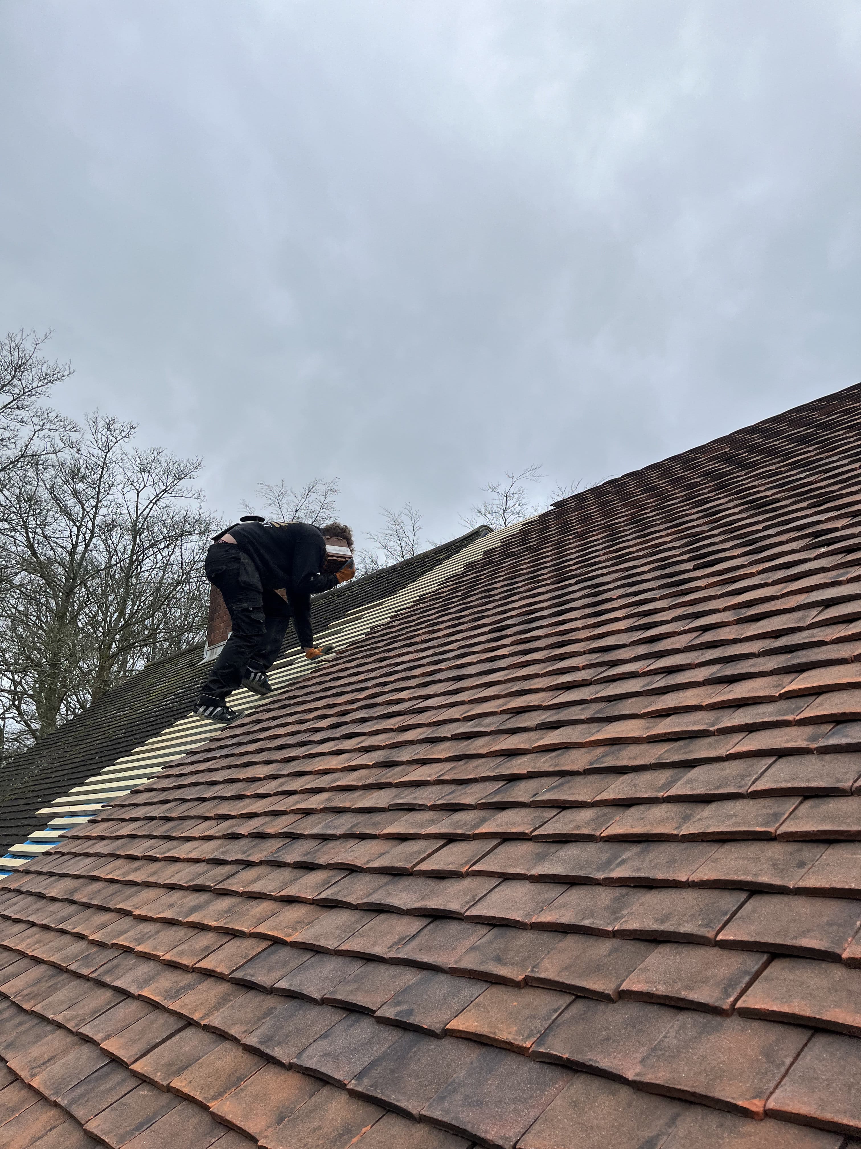 Worker climbing clay tile roof